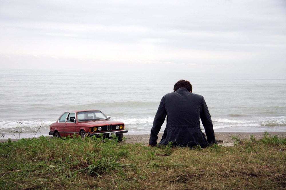 shahab hosseini about elly sitting with the red car at the sea