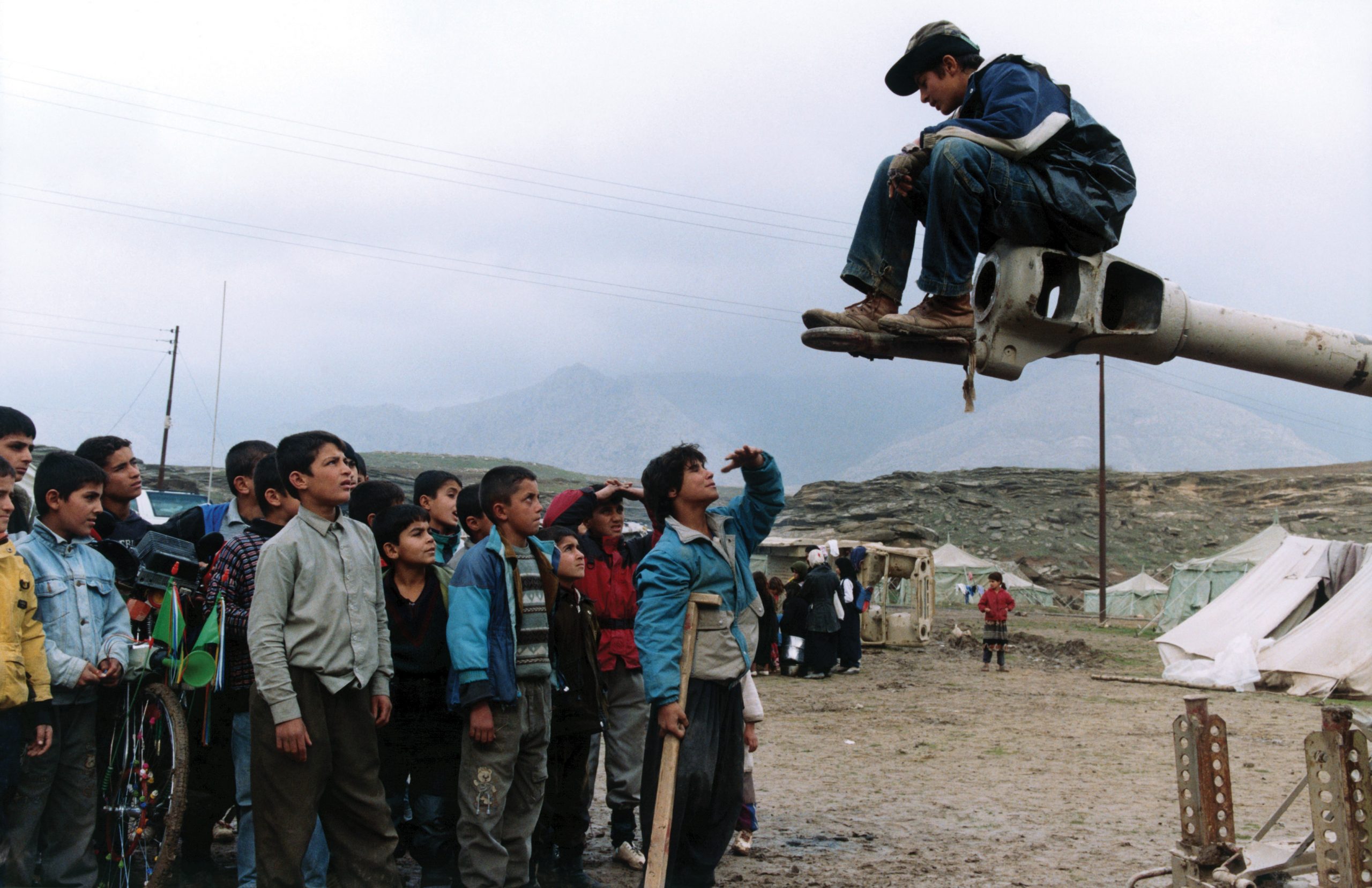 Turtles Can Fly Soran Ebrahim Satellite sitting on tank spkeaking and kids around him 